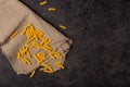 Burlap napkin on a dark structural background, top view. A scattering of macaroni on it Royalty Free Stock Photo