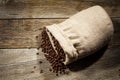 Burlap sack of coffee beans against dark wood background