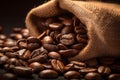 Burlap sack of coffee beans against dark wood background with whole coffee beans spilling out over wood panel Royalty Free Stock Photo