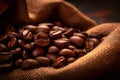 Burlap sack of coffee beans against dark wood background with whole coffee beans spilling out over wood panel Royalty Free Stock Photo