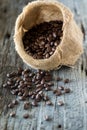 A burlap sack filled with coffee beans and a pile spilled out in front. Royalty Free Stock Photo