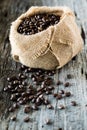 A burlap sack filled with coffee beans wth some spilled out in front. Royalty Free Stock Photo