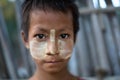 Burmese child with traditional Thanaka face paint poses for portrait