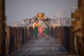 Burmese Family walks home from market along wooden footbridge at sunrise