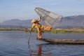 Burmese fisherman on bamboo boat catching fish in traditional way with handmade net. Inle lake, Myanmar, Burma Royalty Free Stock Photo