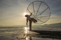 Burmese fisherman on bamboo boat catching fish in traditional way with handmade net. Inle lake, Myanmar, Burma Royalty Free Stock Photo