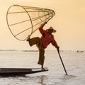 Burmese fisherman on bamboo boat catching fish in traditional way with handmade net. Inle lake, Myanmar (Burma) Royalty Free Stock Photo