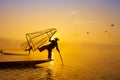 Burmese fisherman on bamboo boat catching fish in traditional way with handmade net. Inle lake, Myanmar Burma travel destination Royalty Free Stock Photo