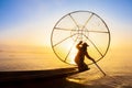 Burmese fisherman on bamboo boat catching fish in traditional way with handmade net. Inle lake, Myanmar Burma travel destination Royalty Free Stock Photo