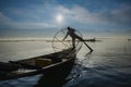 Burmese fisherman on bamboo boat catching fish in traditional way with handmade net. Royalty Free Stock Photo