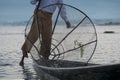 Burmese fisherman on bamboo boat catching fish in traditional way with handmade net. Royalty Free Stock Photo