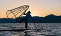 Burmese fisherman posing for tourists at sunset.