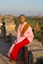 Burmese girl-a nun is sitting on a background of ancient Buddhist temples of Bagan