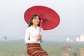 A Burmese girl is siting with a red umbrella. Woman in the longest teak bridge in Asia.U-bein bridge, Mandalay, Myanmar Royalty Free Stock Photo