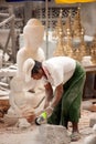 Burmese man carving a large marble Buddha statue.