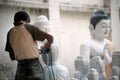 Burmese man carving a large marble Buddha statue.