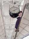 Burmese Man setting time on a big clock in (Rangoon) Yangon, (Burma) Myanma