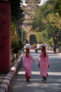 Burmese nuns women put holding tray on head walking on street at beside road front of ancient ruins building of Mandalay Palace go