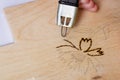Burn out a drawing on a wooden board with an electric device with a scorcher Royalty Free Stock Photo