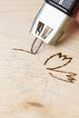 Burn out a drawing on a wooden board with an electric device with a scorcher Royalty Free Stock Photo