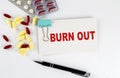 BURN OUT text written in a card with pills. Medical concept