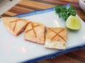 Burn salmon belly cut in cross shape on served with lemon lime and japanese vegetable leaf on a white plate in japanese style Royalty Free Stock Photo