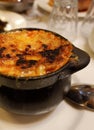 Burned cheese crust on the bowl with French traditional onion soup in restaurant in Pau, France. Vertical photo