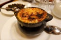 Burned cheese crust on the pot with French traditional onion soup in restaurant in Pau, France