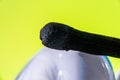 Burned match on the surface of a curly light bulb. On a light green background. Macro Royalty Free Stock Photo