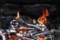 Burned Wood with flames still burning, dark Stone Background of camp fire or Grill Royalty Free Stock Photo