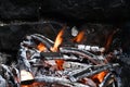 Burned Wood with flames still burning, dark Stone Background of camp fire or Grill Royalty Free Stock Photo