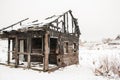 Burned wooden house on a white snow