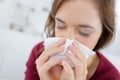 Burnette woman blowing nose into tissue