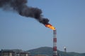 Burning accompanying gas from refinery stack against blue sky