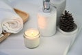 Burning aromatic candle, towels and bottles on white table. Royalty Free Stock Photo