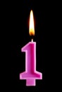 Burning birthday candle in the form of 1 one figures for cake isolated on black background. The concept of celebrating a birthday, Royalty Free Stock Photo