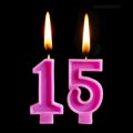 Burning birthday candles in the form of 15 fifteen figures for cake isolated on black background. The concept of celebrating a bir