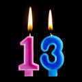 Burning birthday candles in the form of 13 thirteen figures for cake isolated on black background. Royalty Free Stock Photo