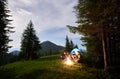 Burning bonfire in evening campsite and people around it enjoy the view of valley powerful mountains