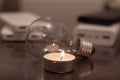 A burning candle against the background of a light bulb and power banks Royalty Free Stock Photo