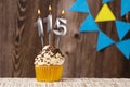 Burning candle - birthday number 115 on wooden background with pennants
