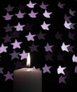 Burning candle with blur violet stars on black background Royalty Free Stock Photo