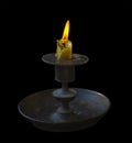 The burning candle burns out. Old bronze antique candlestick on a black background isolated . Vintage item Royalty Free Stock Photo