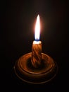 Burning candle in a candlestick on a black background Royalty Free Stock Photo
