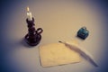 Burning candle in candlestick, letter paper blank, quill pen, inkwell on the table. Vintage style filtered photo Royalty Free Stock Photo