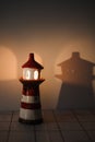 burning candle in a candlestick in the shape of a lighthouse with a shadow, cozy warm atmosphere