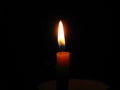 Burning candle in center position and dark background, copyspace.