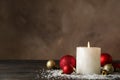 Burning candle and christmas balls on background with snow, space for text