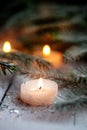 Burning candle and Christmas decoration over snow with pine branches on white wooden background Royalty Free Stock Photo