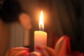 Burning candle in the church. Silence prayer moment with candle light, blurry pink flowers & hand of Mother Mary in the backgroud. Royalty Free Stock Photo